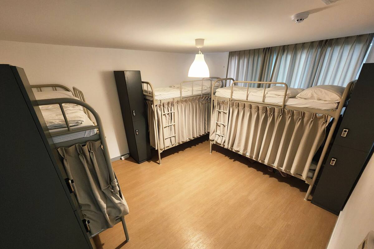 A dormitory room with bunk beds, a wardrobe, and a desk.