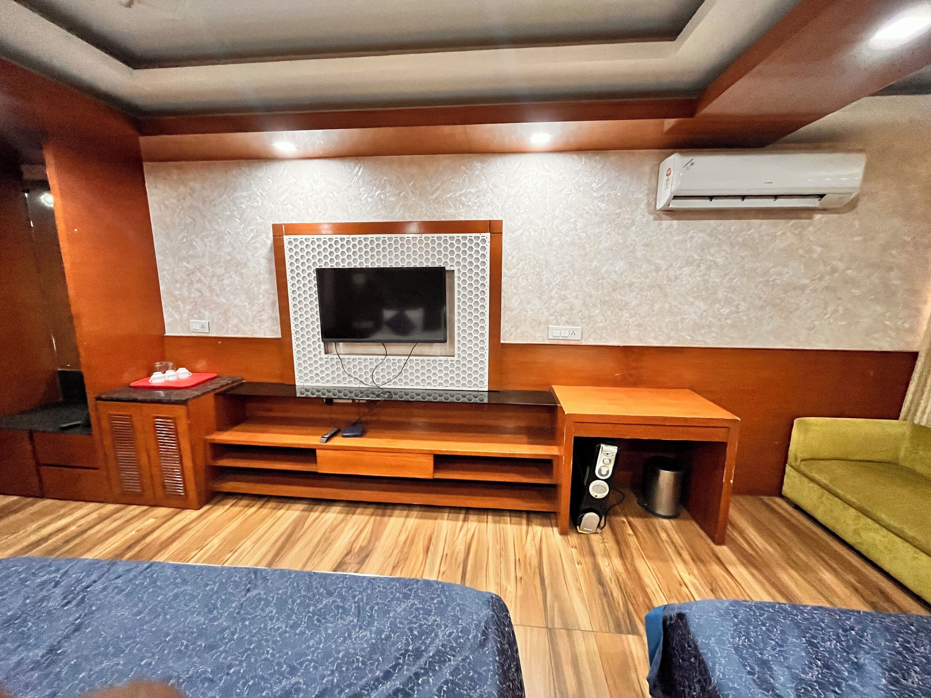 A room with a wooden entertainment unit, a television, and a green sofa.