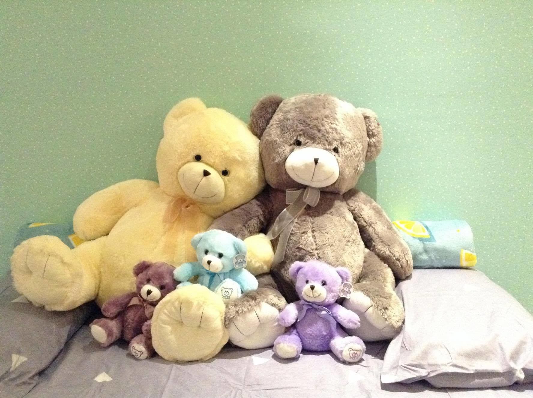 A bed with multiple teddy bears of various sizes and colors.