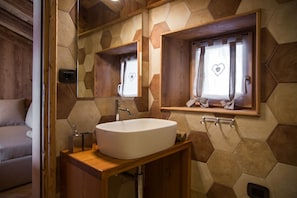 A bathroom with a large oval sink, wooden vanity, and a mirror above the sink.