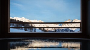 A window view of snow-covered mountains, a clear sky, and a reflection of the mountains in a body of water below. - Lavarets Chambres d'Hotes (Ayas)