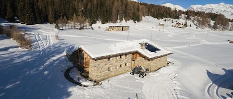 A snow-covered mountain landscape with a stone cabin and a ski lift.