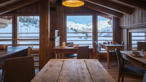 A rustic wooden interior with large windows offering a snowy mountain view. - Lavarets Chambres d'Hotes (Ayas)