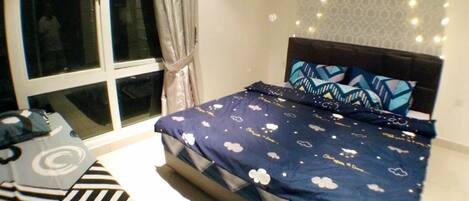 A bedroom with a bed, a window, and a wall-mounted light fixture.