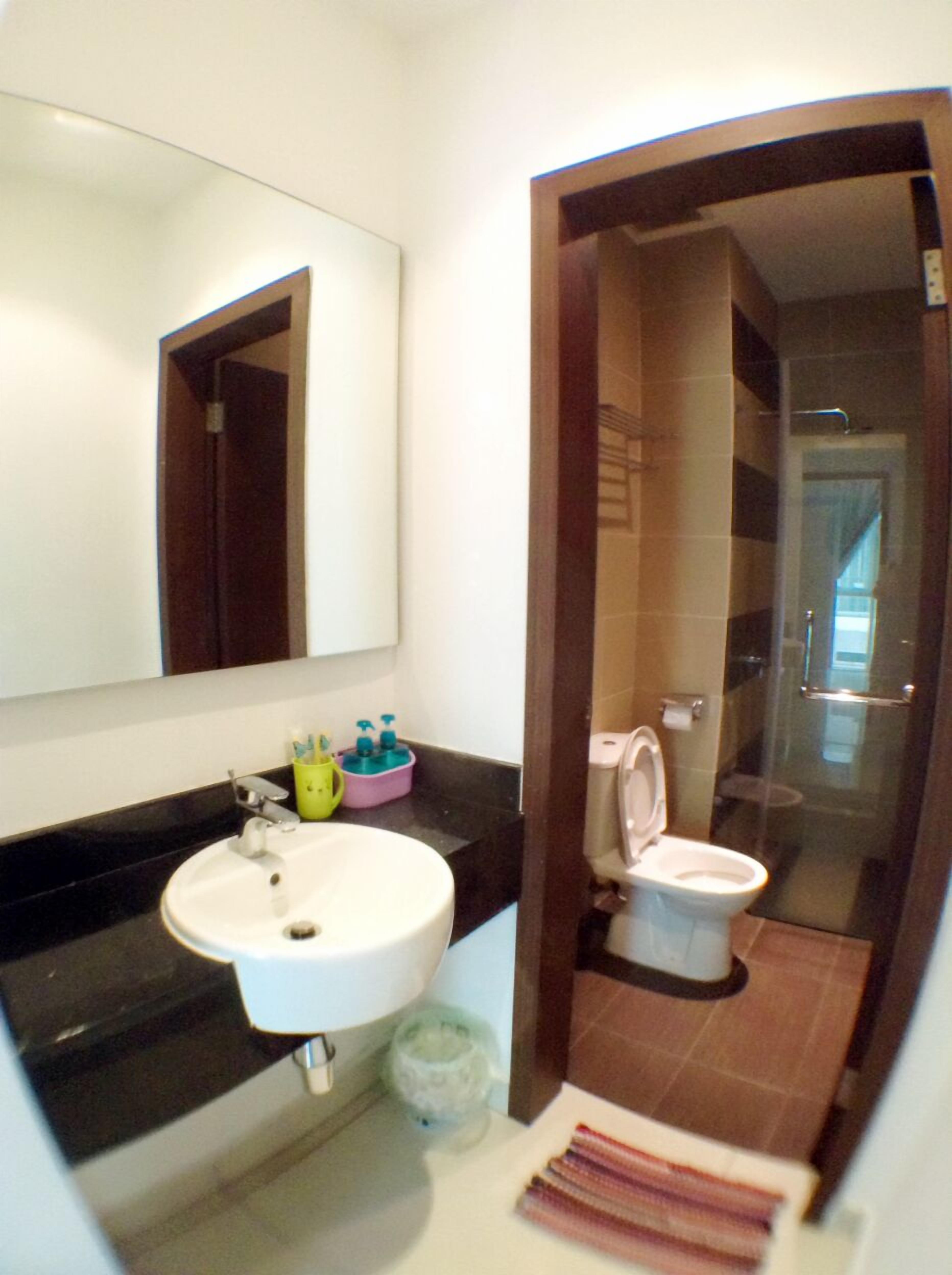 Une salle de bain équipée d’un lavabo, d’un miroir, de toilettes et d’une zone douche.