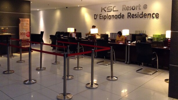 Uma área de recepção no KSL Resort, com um balcão, cadeiras e uma barreira vermelha.