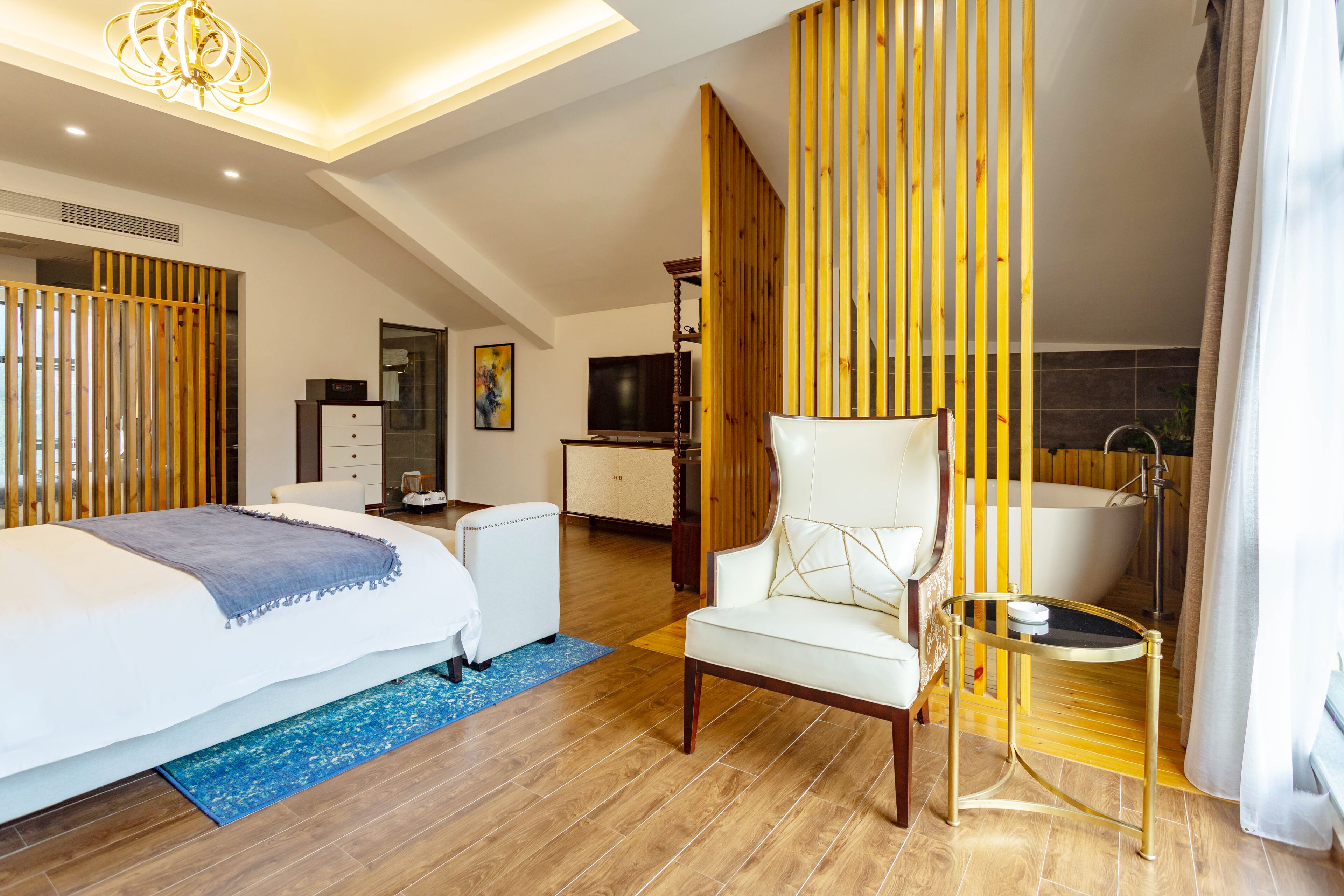 Une chambre d’hôtel moderne dotée d’un grand lit, d’un coin salon, d’une télévision, d’un bureau et d’une baignoire.