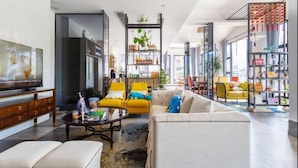 A modern living room with a sofa, armchairs, a coffee table, and a television.