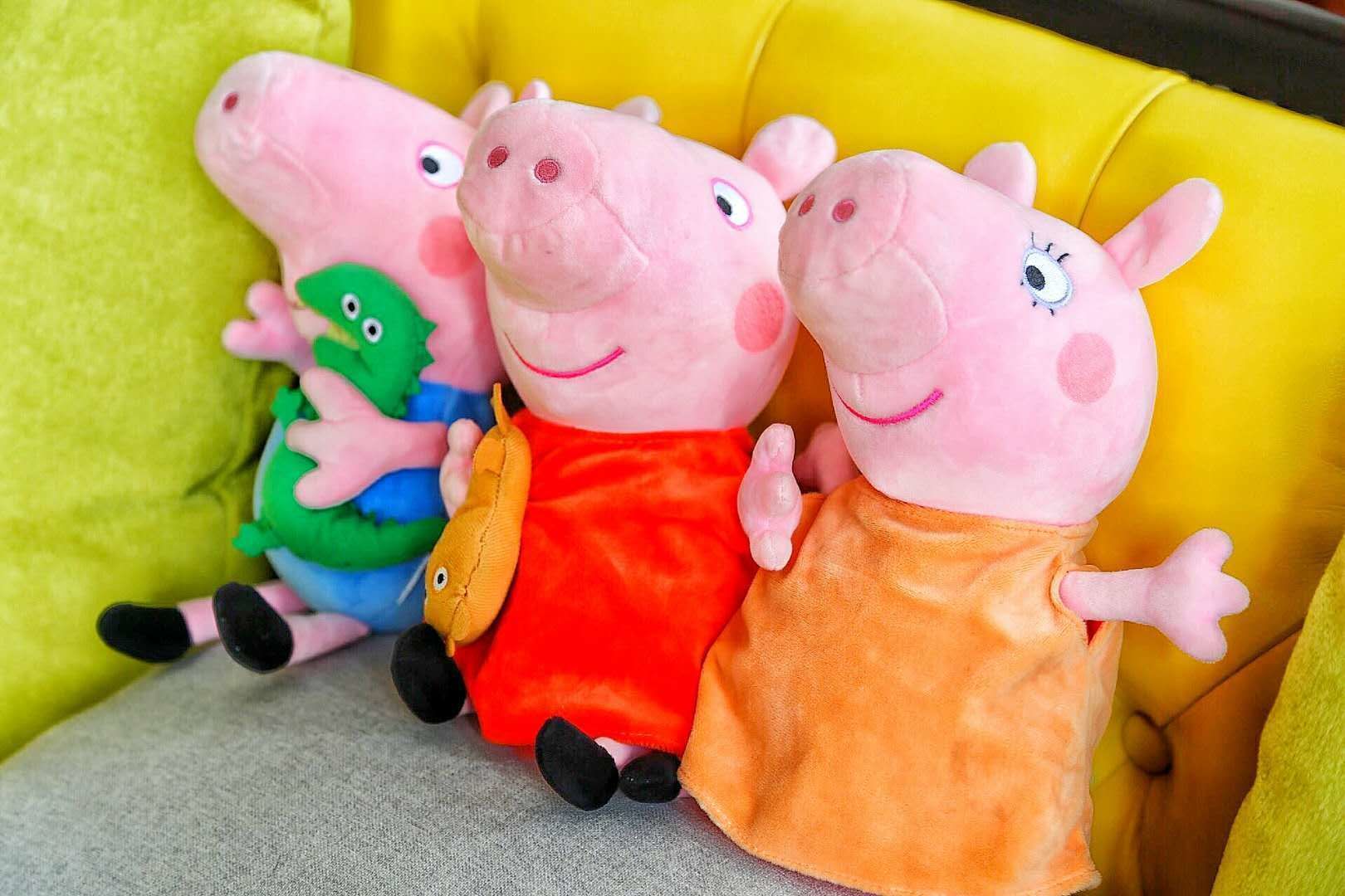 Three plush toys sitting on a yellow couch with a green pillow.