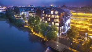 A multi-story hotel with balconies, a riverside location, and a well-lit facade.