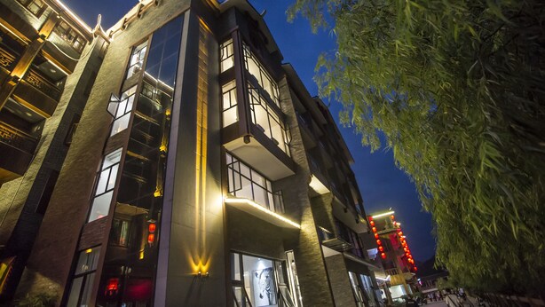A multi-story building with balconies and large windows, featuring modern architecture and illuminated exterior lighting.