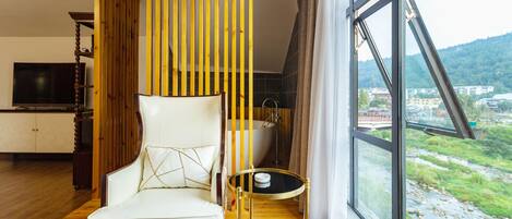 Ein modernes Zimmer mit einem großen Fenster, einem weißen Sofa, einem kleinen runden Tisch und einer Holzvertäfelung.