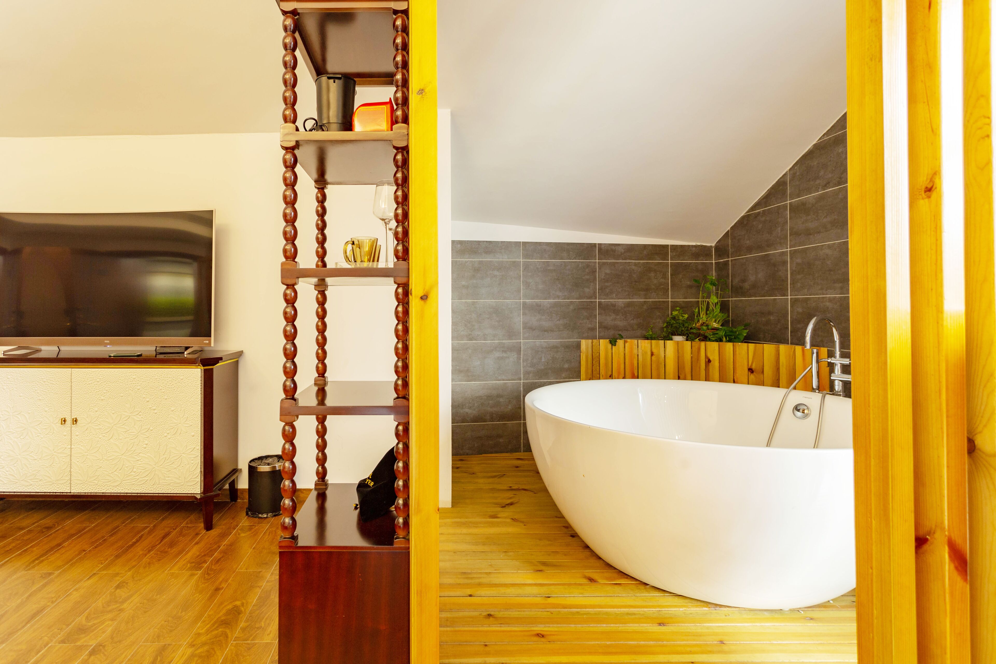 Un baño moderno con una bañera independiente, suelo de madera y una estantería empotrada.