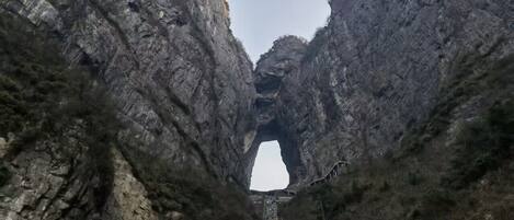 A stone bridge with Chinese characters, leading to a natural rock formation.