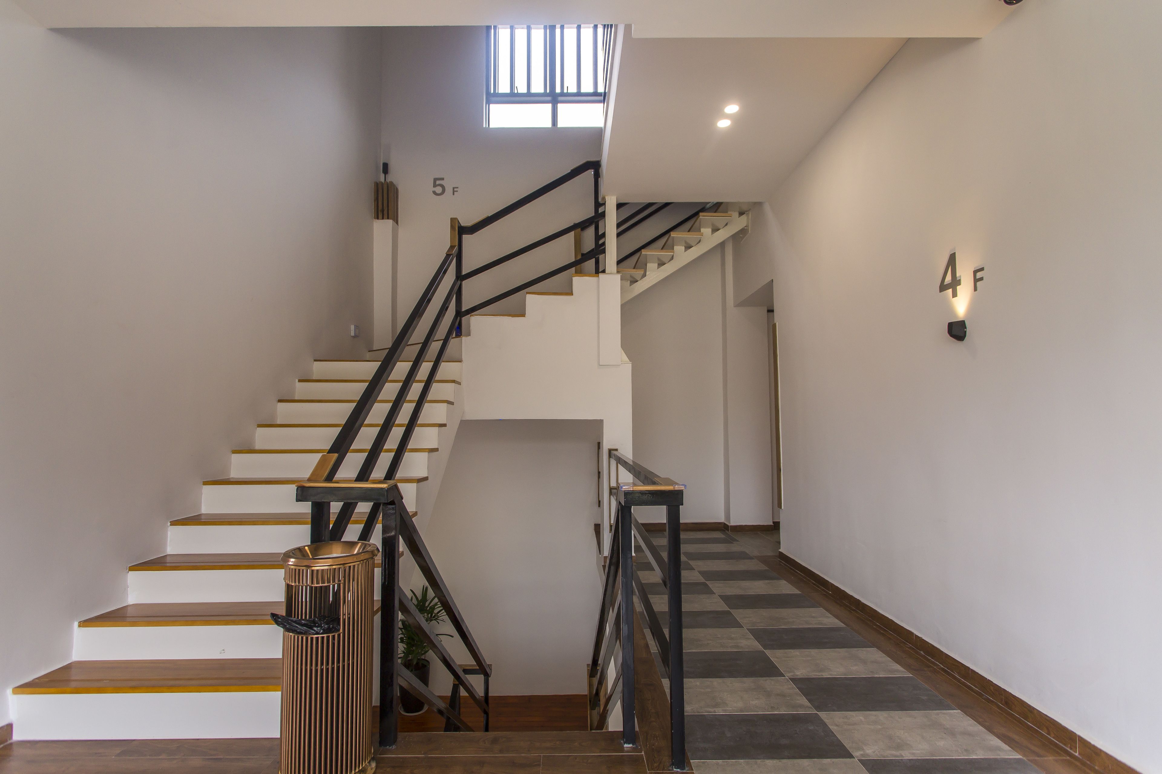 Un escalier avec des marches en bois et des rampes noires, menant à l’étage supérieur.