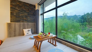 A modern room with a large window, a wooden bench, and a view of a lush green landscape.
