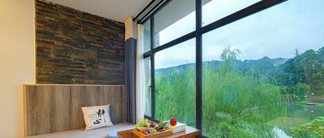 A modern room with a large window, a wooden bench, and a view of a lush green landscape.