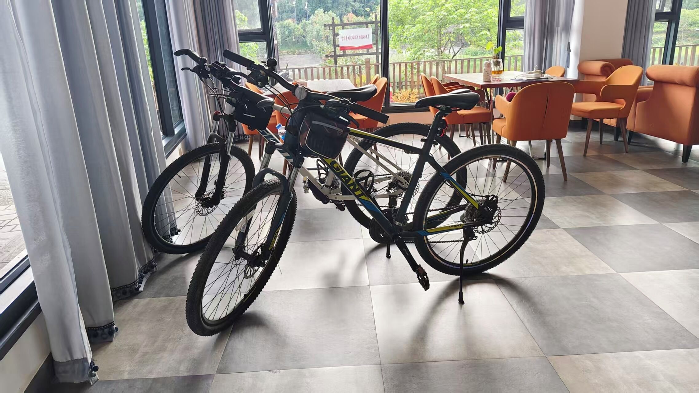 A bicycle in a room with a view of greenery outside.