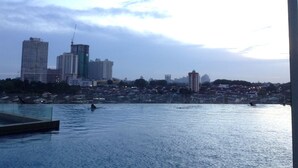 A city skyline with high-rise buildings and a body of water in the foreground. - HomeStay in Johor - KSL SeaView (Johor Bahru)