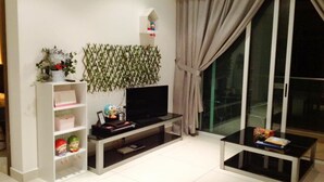 A modern living room with a flat-screen TV, a glass coffee table, and a bookshelf. - HomeStay in Johor - KSL SeaView (Johor Bahru)
