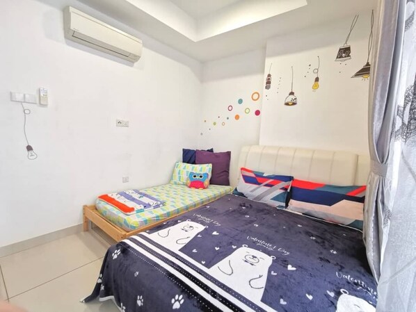 A bedroom with a bed, a bedside table, a wall-mounted air conditioner, and a power outlet. - Homestay in Johor - Secret Garden (Johor Bahru)