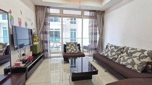 A modern living room with a flat-screen TV, a glass coffee table, and a sofa with patterned cushions. - Homestay in Johor - Secret Garden (Johor Bahru)