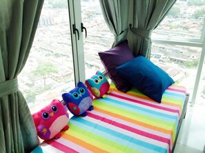 A bed with colorful striped bedding and three plush owl toys. - HomeStay D'Esplanade - Sweet Home (Johor Bahru)