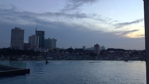 Une vue sur les gratte-ciel d’une ville au crépuscule, avec un plan d’eau au premier plan.