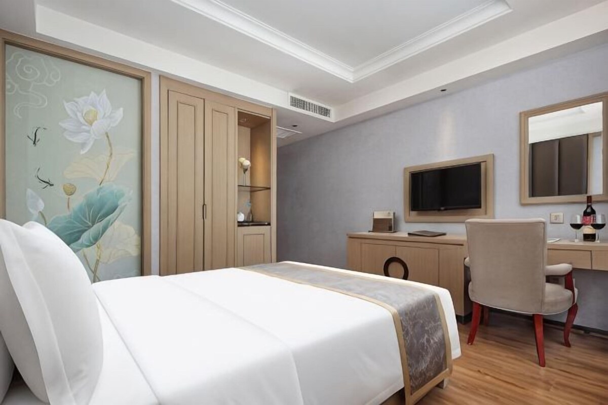 A bedroom with a bed, a desk, a chair, a television, and a wardrobe.
