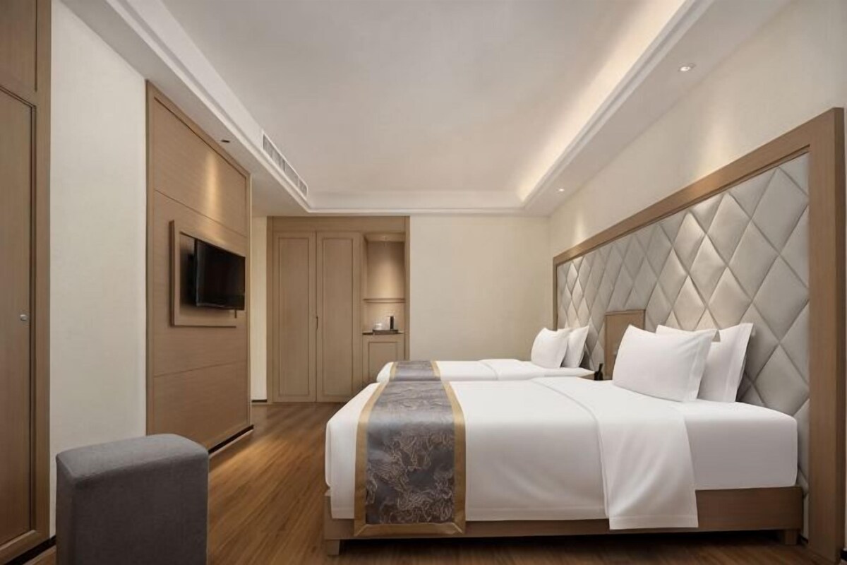 A hotel room with a large bed, a television, and a wardrobe.