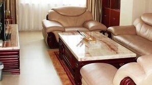 Een woonkamer met een beige bank, een salontafel en een rode kast.