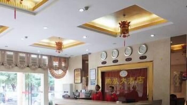 Een hotel receptie met een receptiebalie, een groot raam en een plafond met inbouwverlichting.