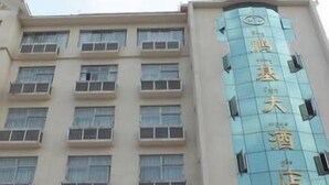 Een hotelgebouw met meerdere verdiepingen, grote ramen en een opvallend bord met Chinese karakters.