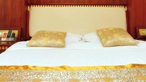 Een hotelkamer met een bed, twee kussens, een nachtkastje en een wand met een bloemenmotief.