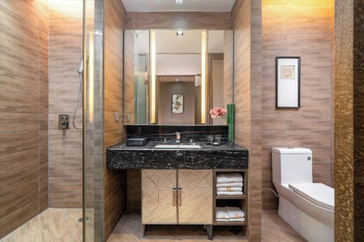 Un baño moderno con ducha acristalada, lavabo de mármol y retrete.