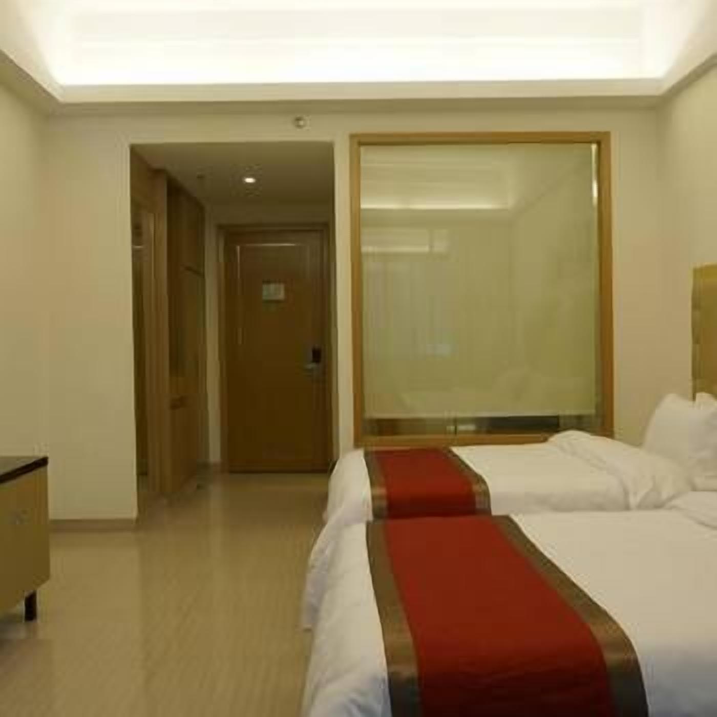 Habitación de hotel con dos camas, un escritorio de madera y un espejo grande.