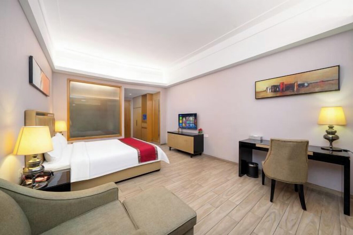Una habitación de hotel con cama, escritorio, silla y televisión.