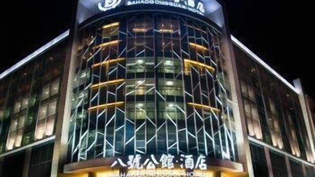 A modern hotel with a curved facade, large glass windows, and illuminated signage. - Bahao Gongguan Hotel (Dongguan)