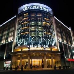 Un hotel moderno con fachada curva, amplios ventanales de vidrio y señalización iluminada.