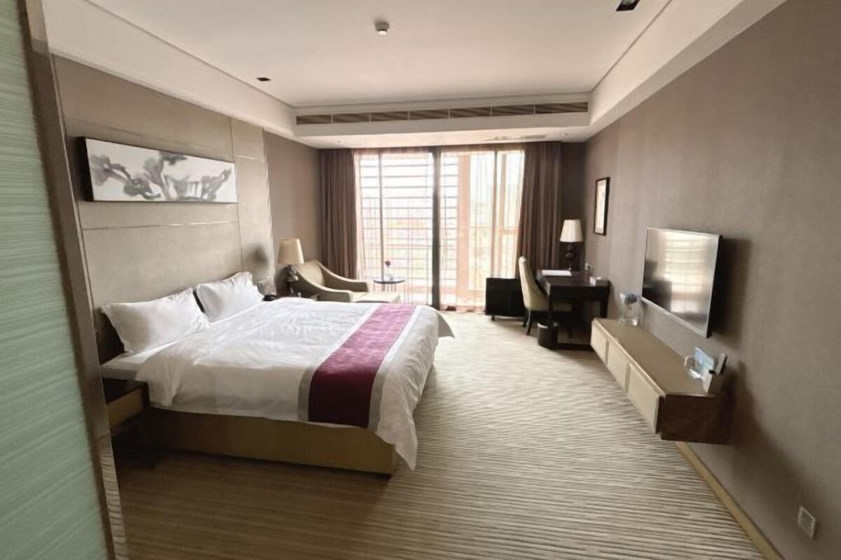 Una habitación de hotel con una cama grande, un escritorio, una silla y un televisor.