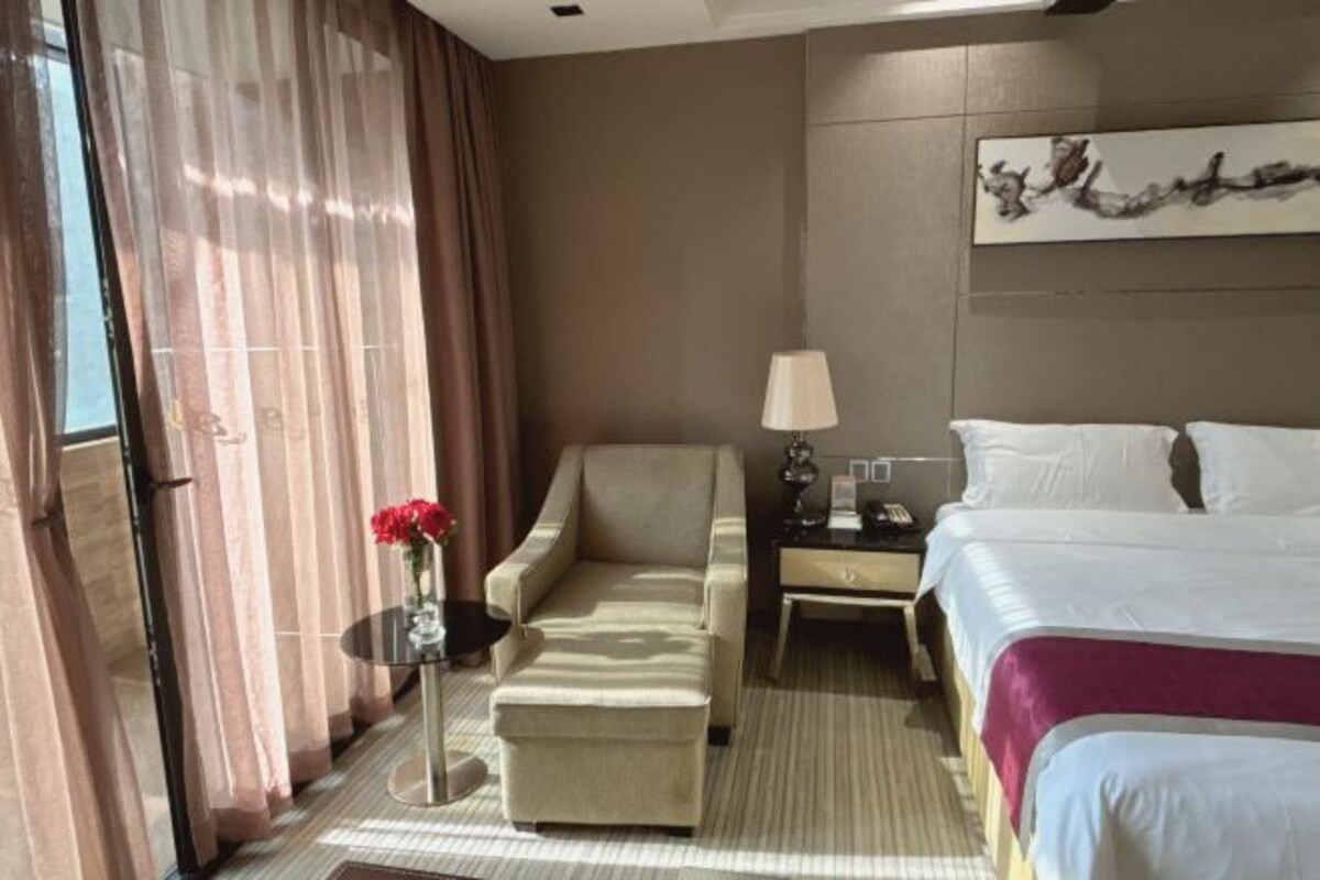 Una habitación de hotel con una cama, un sofá, una mesita con lámpara y un objeto decorativo en la pared.