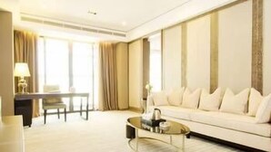 A modern hotel room with a large sofa, a round coffee table, and a dining area with a table and chairs. - Bahao Gongguan Hotel (Dongguan)