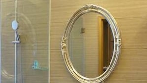 A bathroom with a glass shower enclosure, a white sink, and a round mirror on the wall. - Bahao Gongguan Hotel (Dongguan)