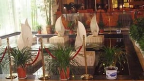 Um hall de entrada com balcão de recepção, área de estar e plantas em vasos.
