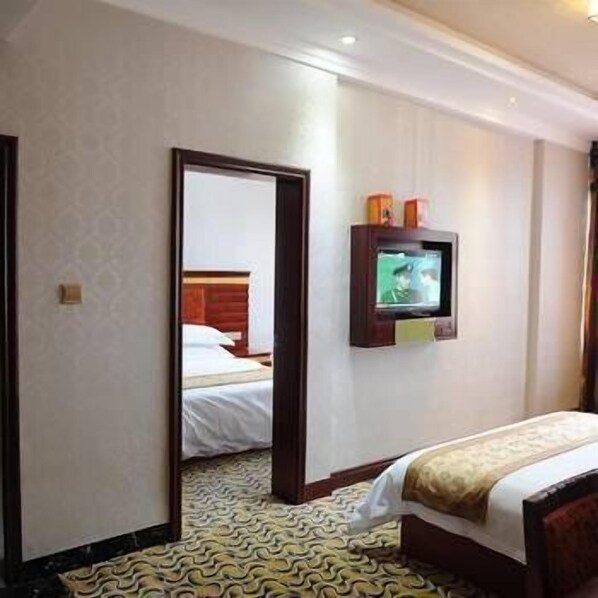 A hotel room with a bed, a television mounted on the wall, and a patterned carpet. - Nanyue Tianji Taoyuan Hotel (Hengyang)