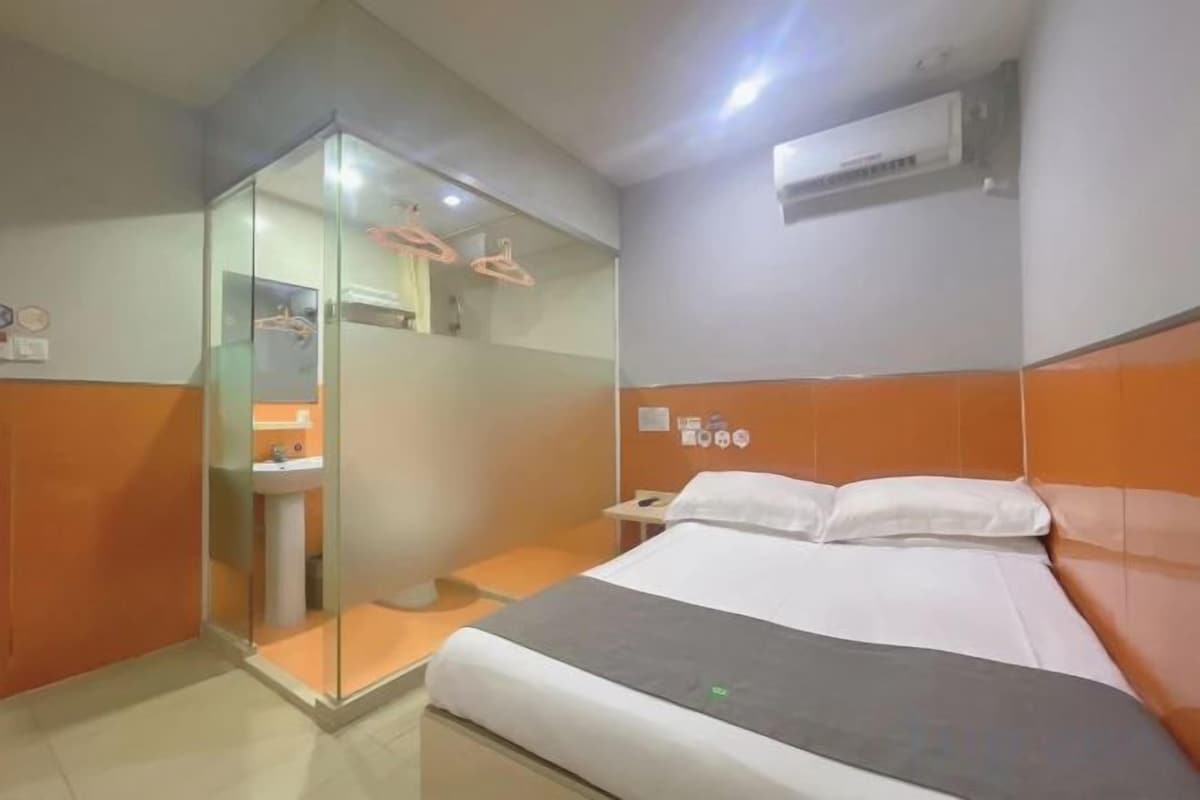 A hotel room with a bed, a shower, and a sink.