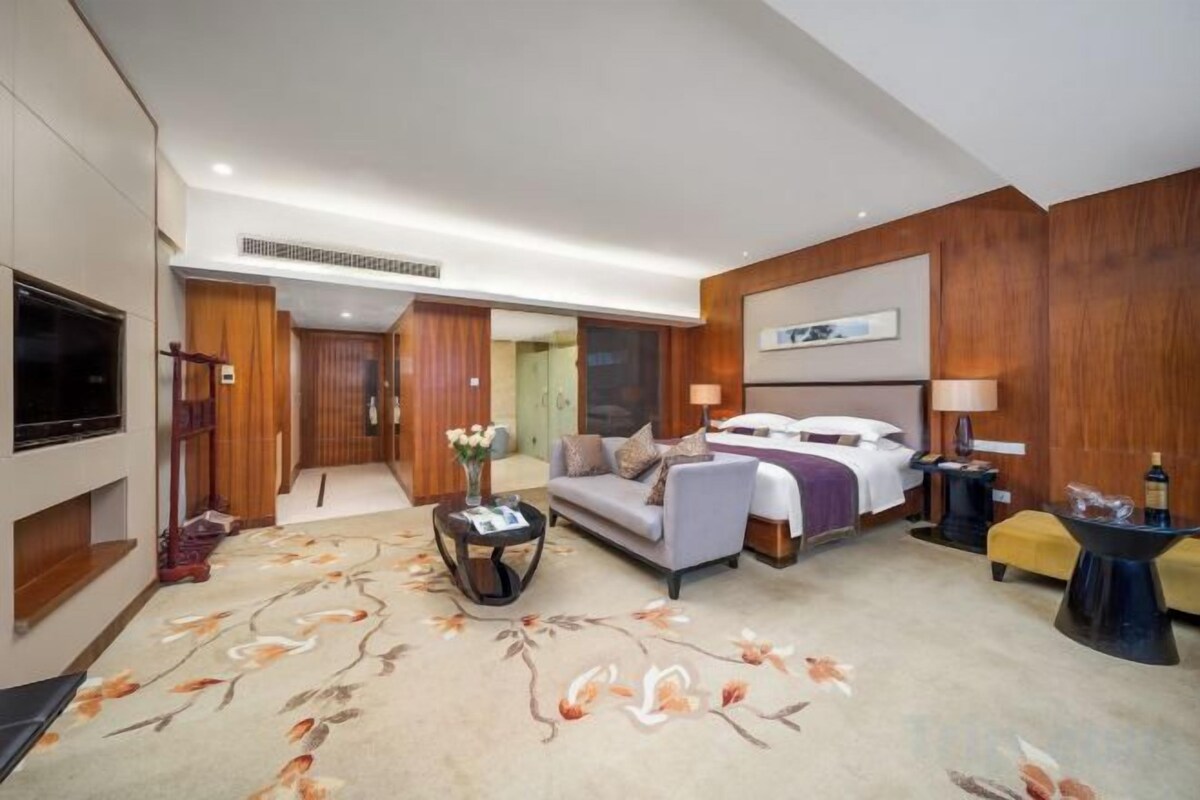 A hotel room with a bed, a TV, a desk, and a sofa.