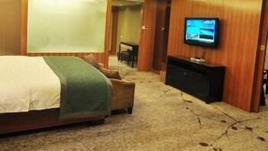 A hotel room with a bed, a television mounted on the wall, and a wooden cabinet. - Fenglin International Hotel (Yulin)