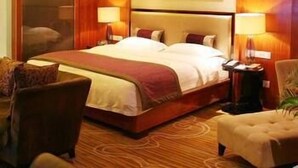 A hotel room with a large bed, two bedside tables, a chair, and a sofa. - Fenglin International Hotel (Yulin)