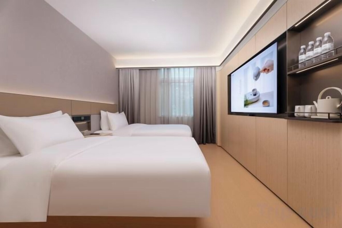 Hotellihuone, jossa on kaksi sänkyä, televisio ja minibaari.